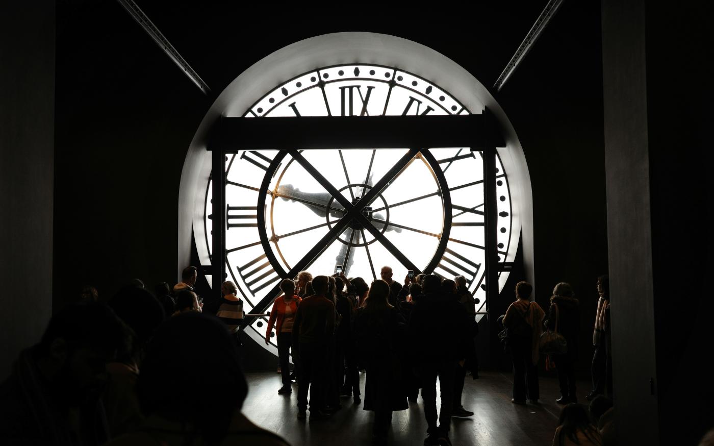 People stand before a giant, illuminated clock. by Hugo Xie courtesy of Unsplash.