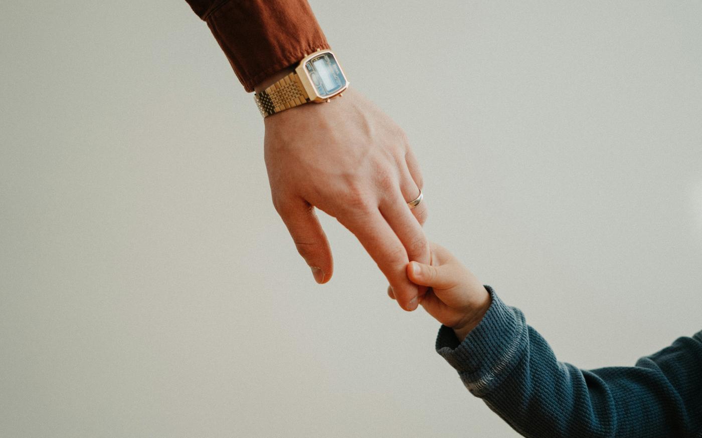 a person holding the hand of a child by Andrik Langfield courtesy of Unsplash.