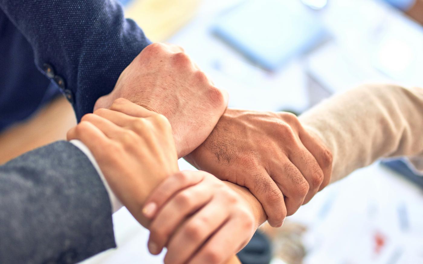 team members gripping wrists in unity gesture by krakenimages courtesy of Unsplash.
