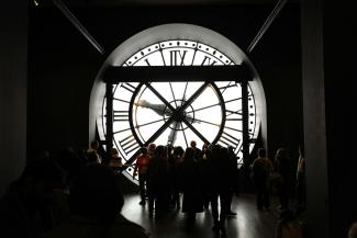 People stand before a giant, illuminated clock. by Hugo Xie courtesy of Unsplash.