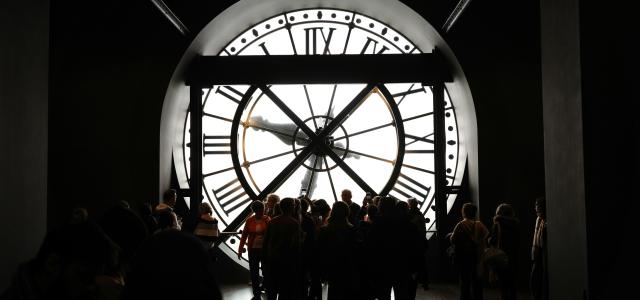 People stand before a giant, illuminated clock. by Hugo Xie courtesy of Unsplash.