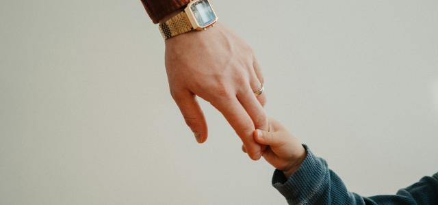 a person holding the hand of a child by Andrik Langfield courtesy of Unsplash.